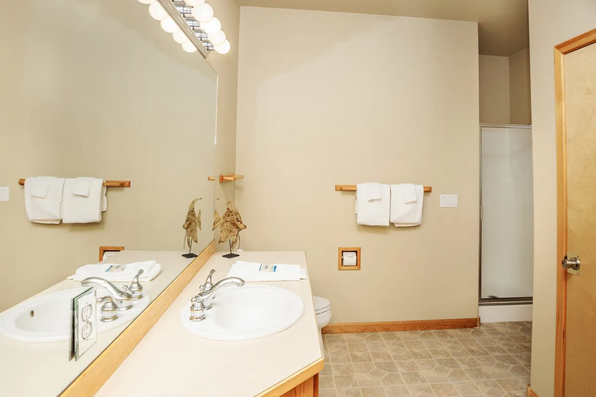 A spa-like bathroom with a mirrored vanity, sleek shower area, and organized sink space. The calm mood and thoughtful details evoke a sense of luxury and relaxation.