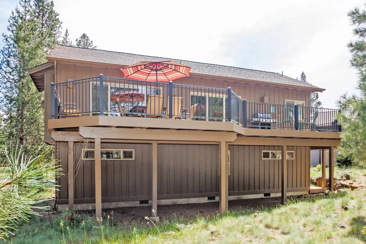 A welcoming deck set with an umbrella, outdoor seating, and a view of surrounding trees. The space is designed for both relaxation and entertaining, naturally extending the home's living area into the outdoors with a direct connection to the landscape.